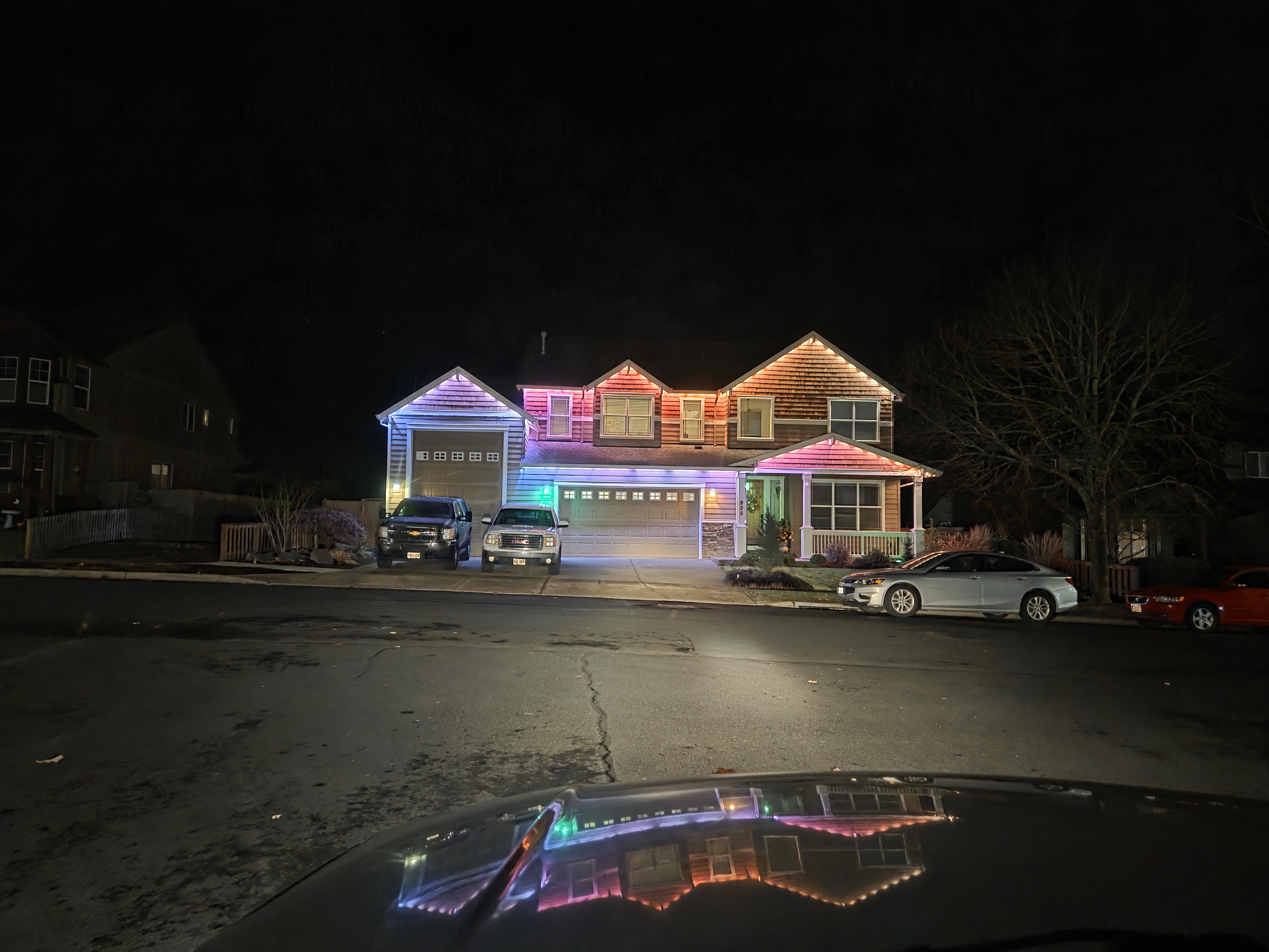 Full rainbow lighting on a home with wet driveway reflection