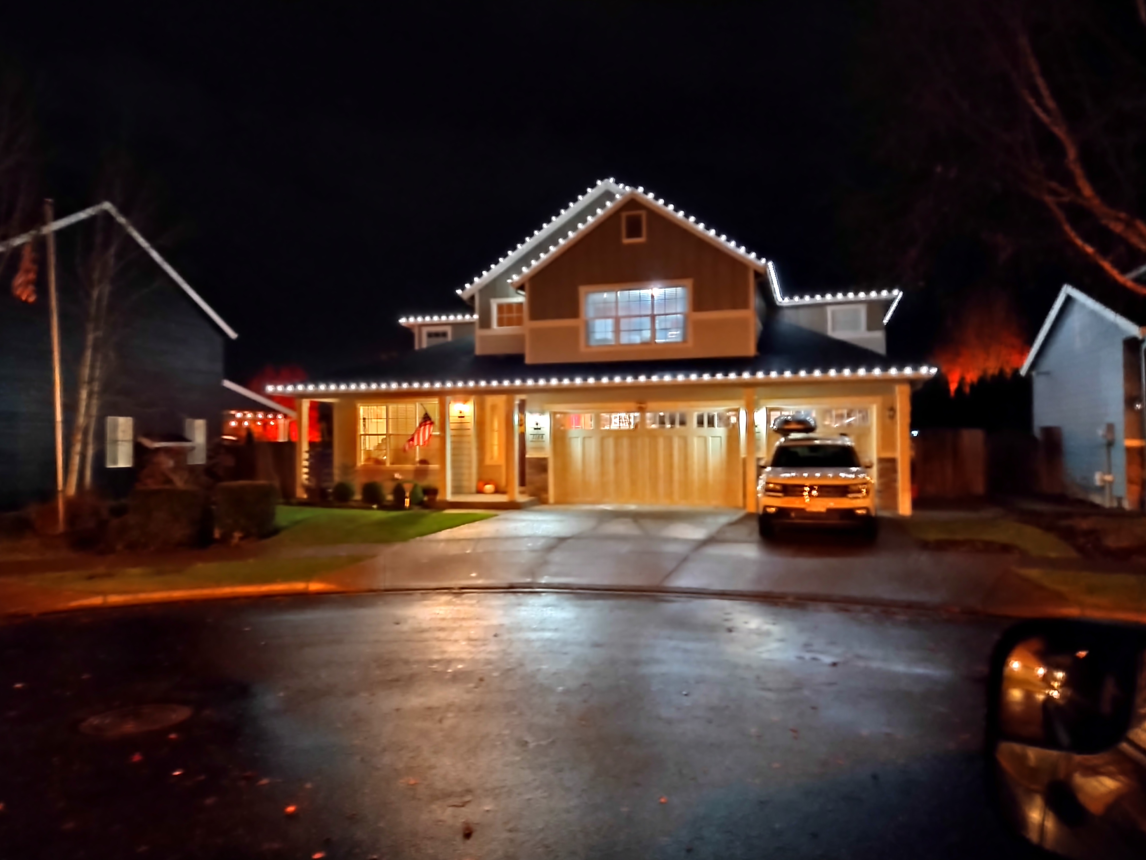 Warm white Christmas lighting on a two-story home and garage