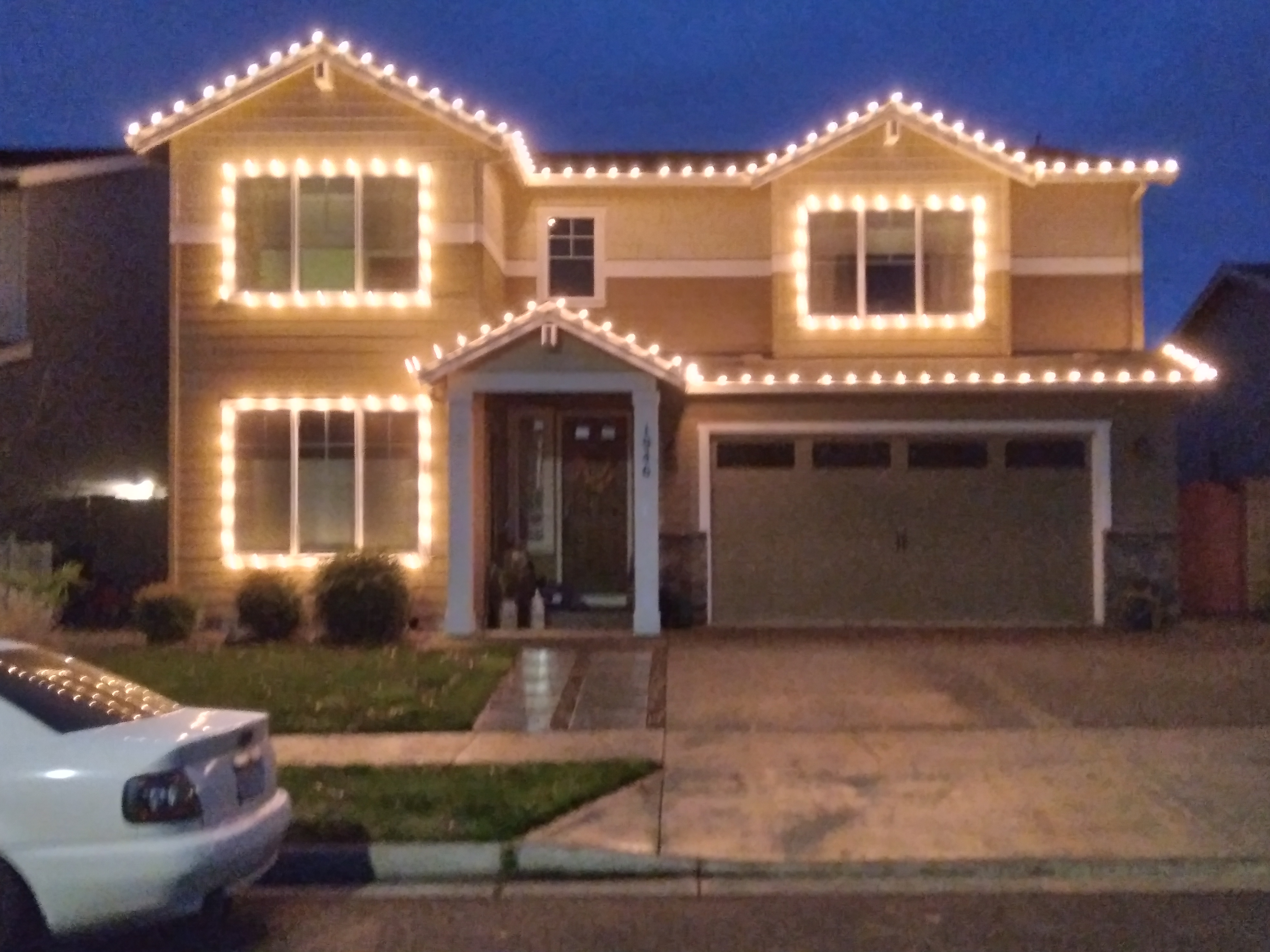 Warm white Christmas lights outlining a home and windows